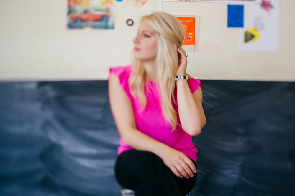 Emily Williams sitting on a blue leather couch wearing a pink shirt and looking off to the side